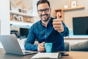 Man sitting at computer making the thumbs up motion